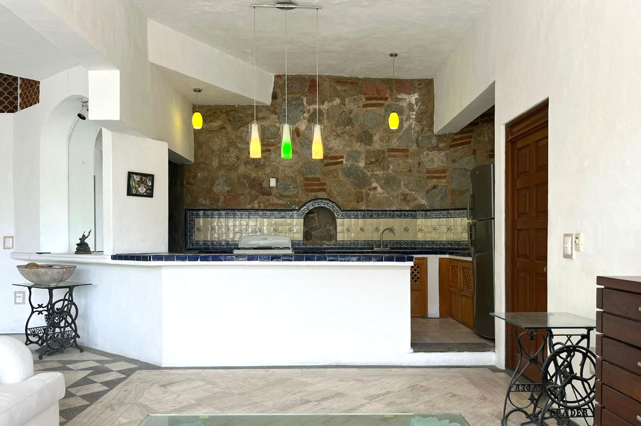 Cocina actual Almejas 6 — isla blanca con azulejo talavera y pared de piedra con campana