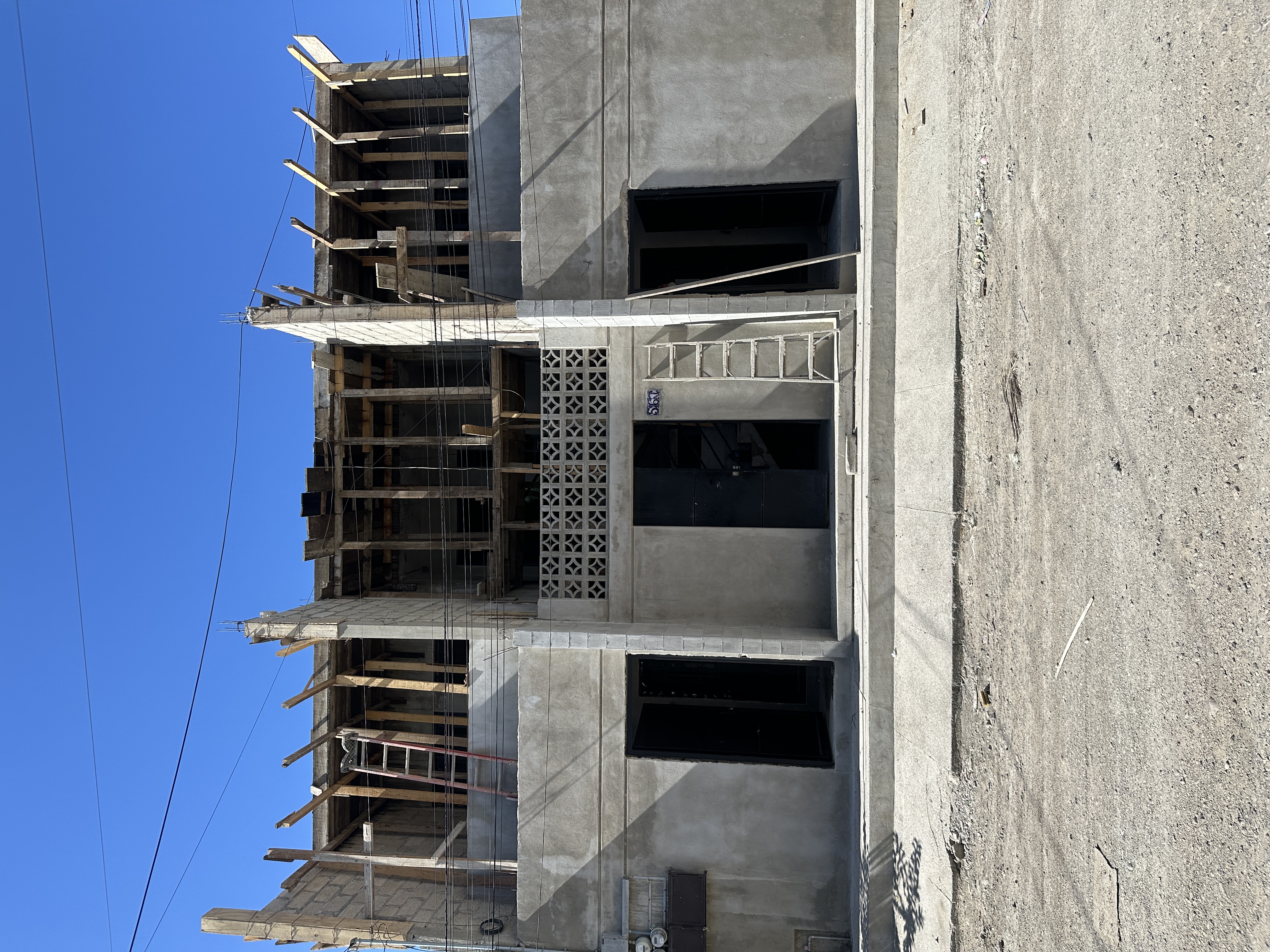 Fachada Argentina Departamentos a media obra — estructura de concreto y celosía artesanal visible