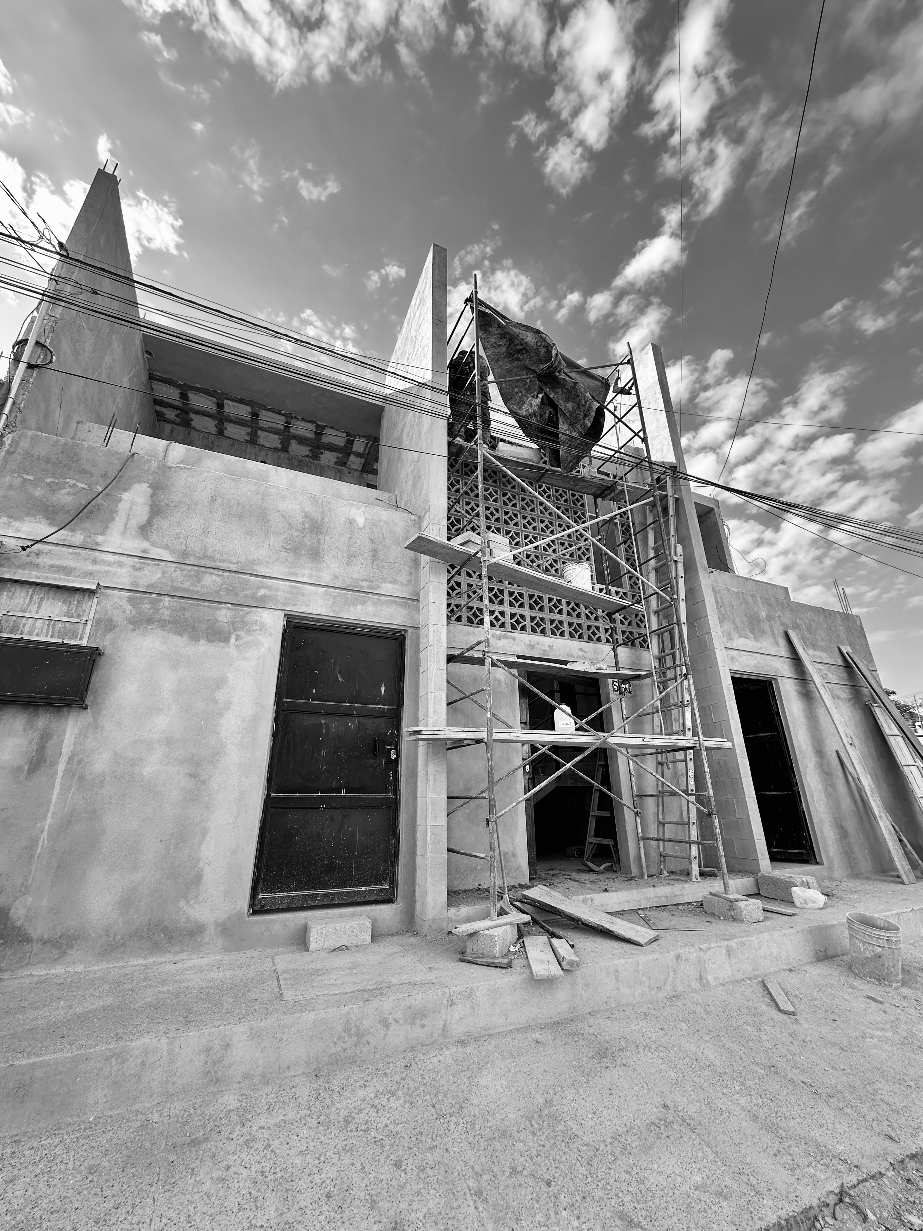Fachada Argentina en blanco y negro durante construcción — andamio y celosía de concreto bajo cielo nublado