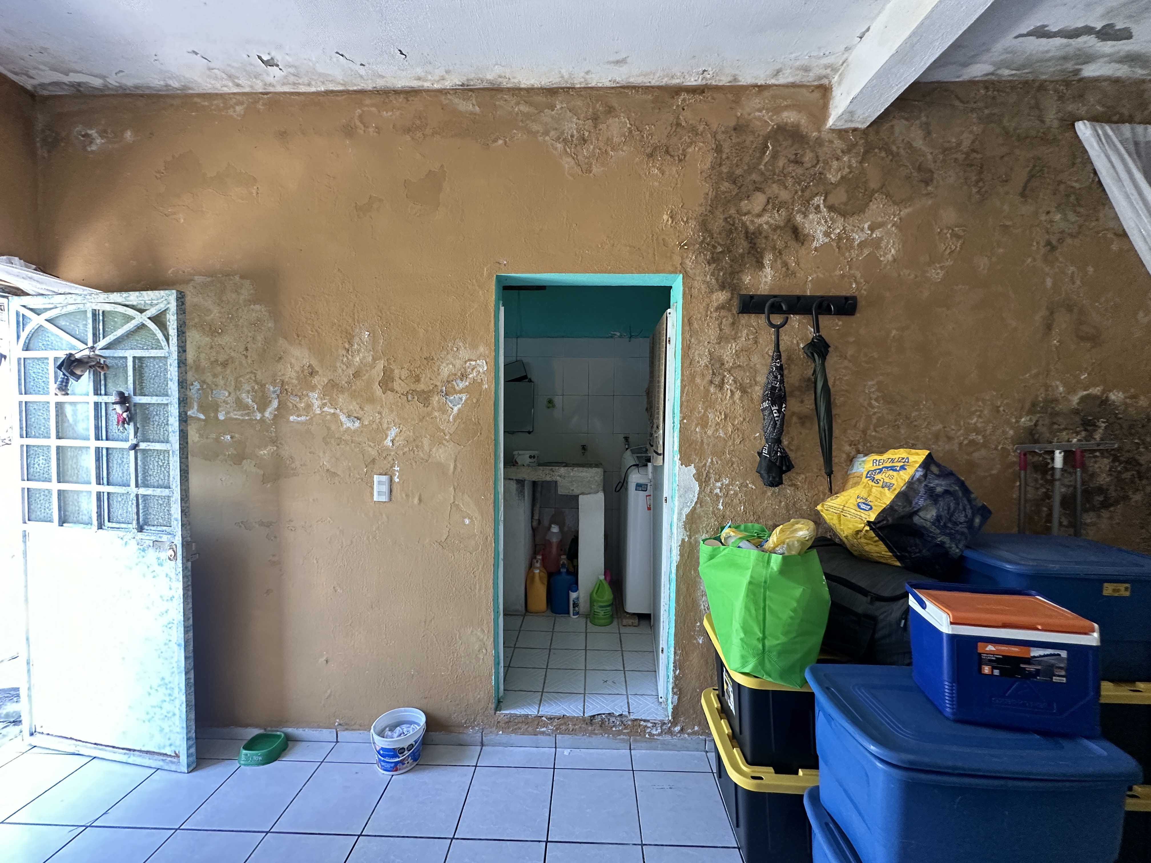 Interior original — sala de la casa con paredes deterioradas antes de la remodelación