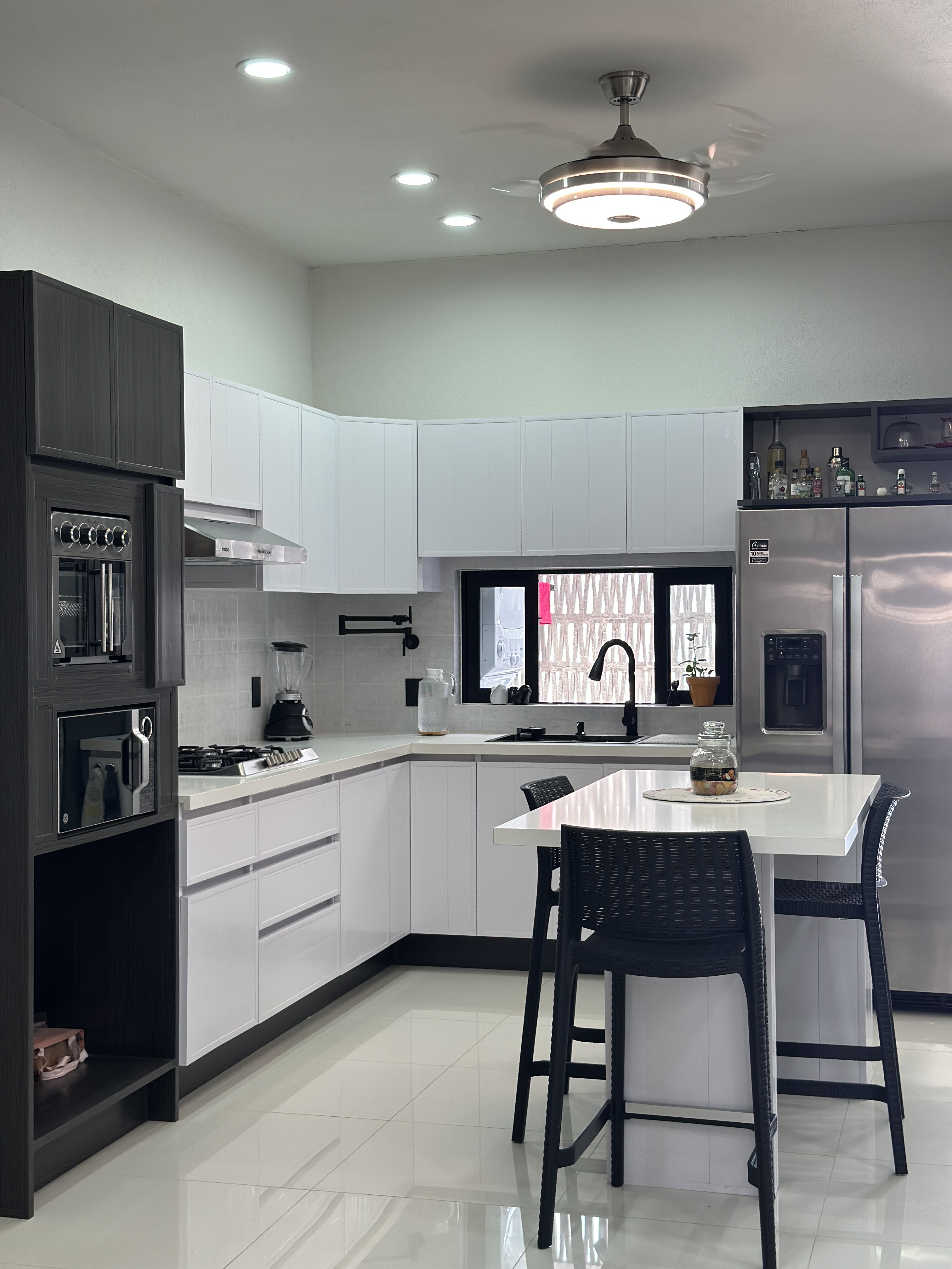 Cocina abierta planta baja — gabinetes blancos, torre de electrodomésticos y isla — Casa Manglar
