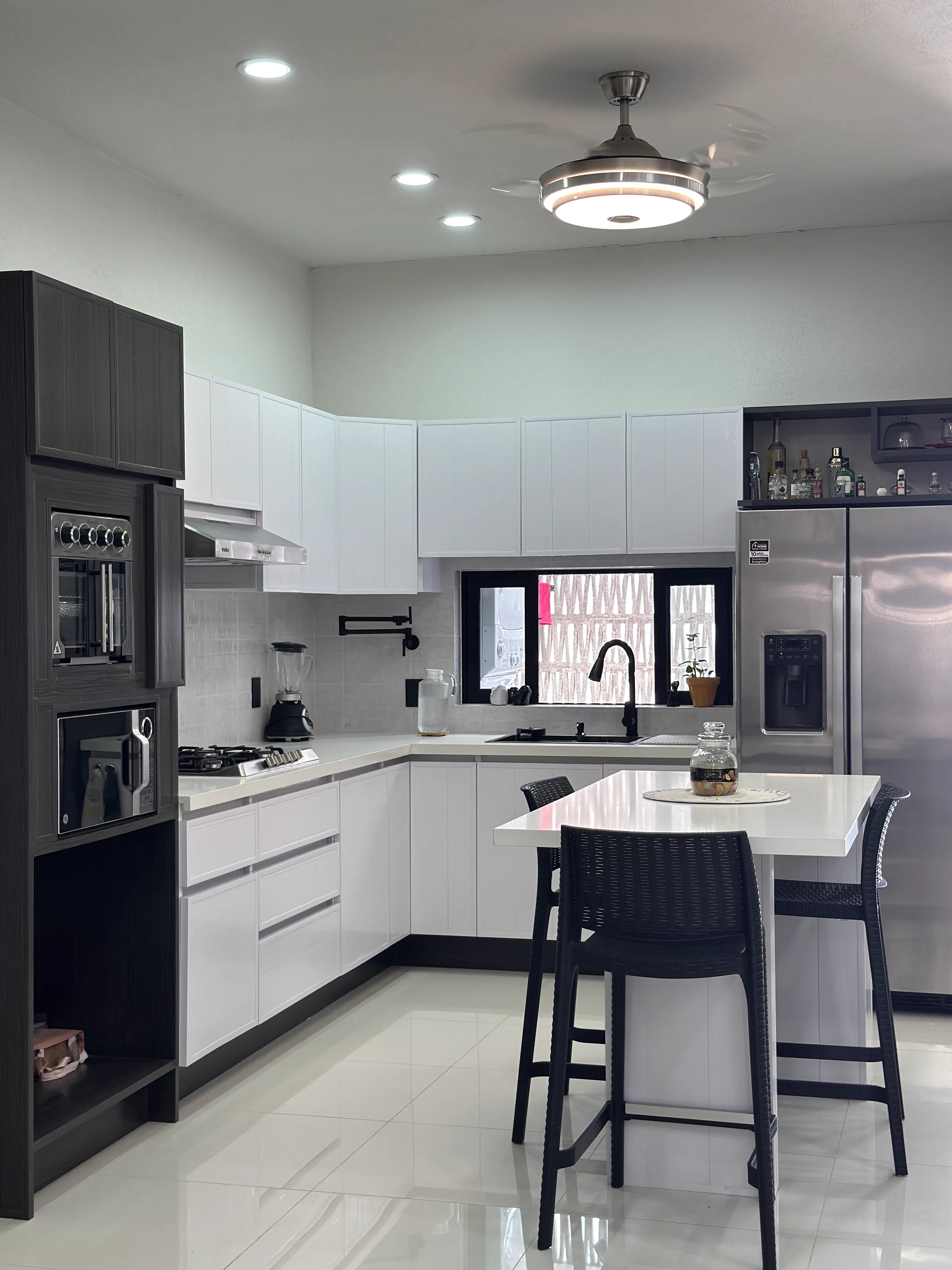 Cocina abierta planta baja — gabinetes blancos, torre de electrodomésticos y isla — Casa Manglar