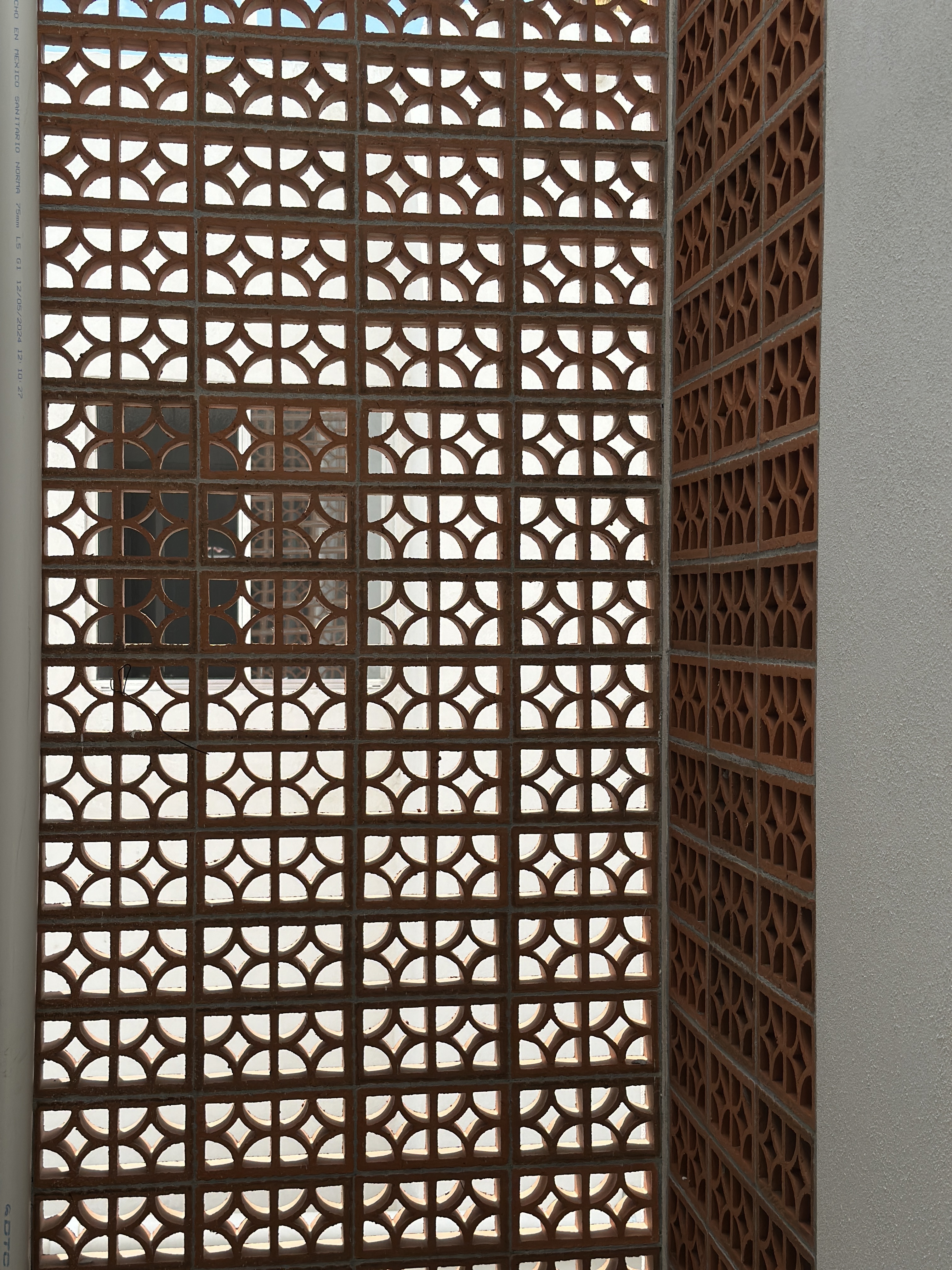 Patrón geométrico de la celosía artesanal de terracota — detalle de fachada Casa Manglar