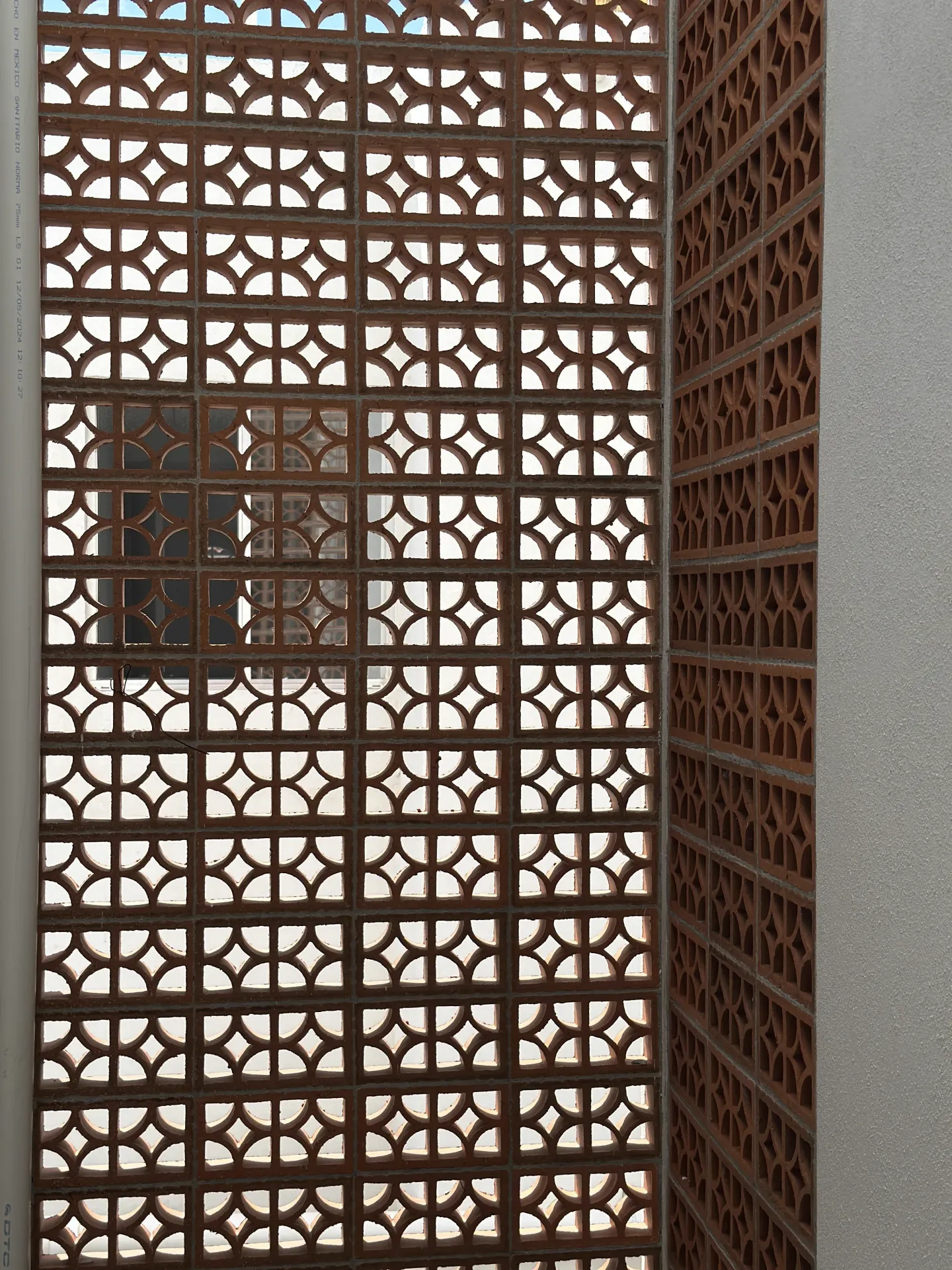 Patrón geométrico de la celosía artesanal de terracota — detalle de fachada Casa Manglar