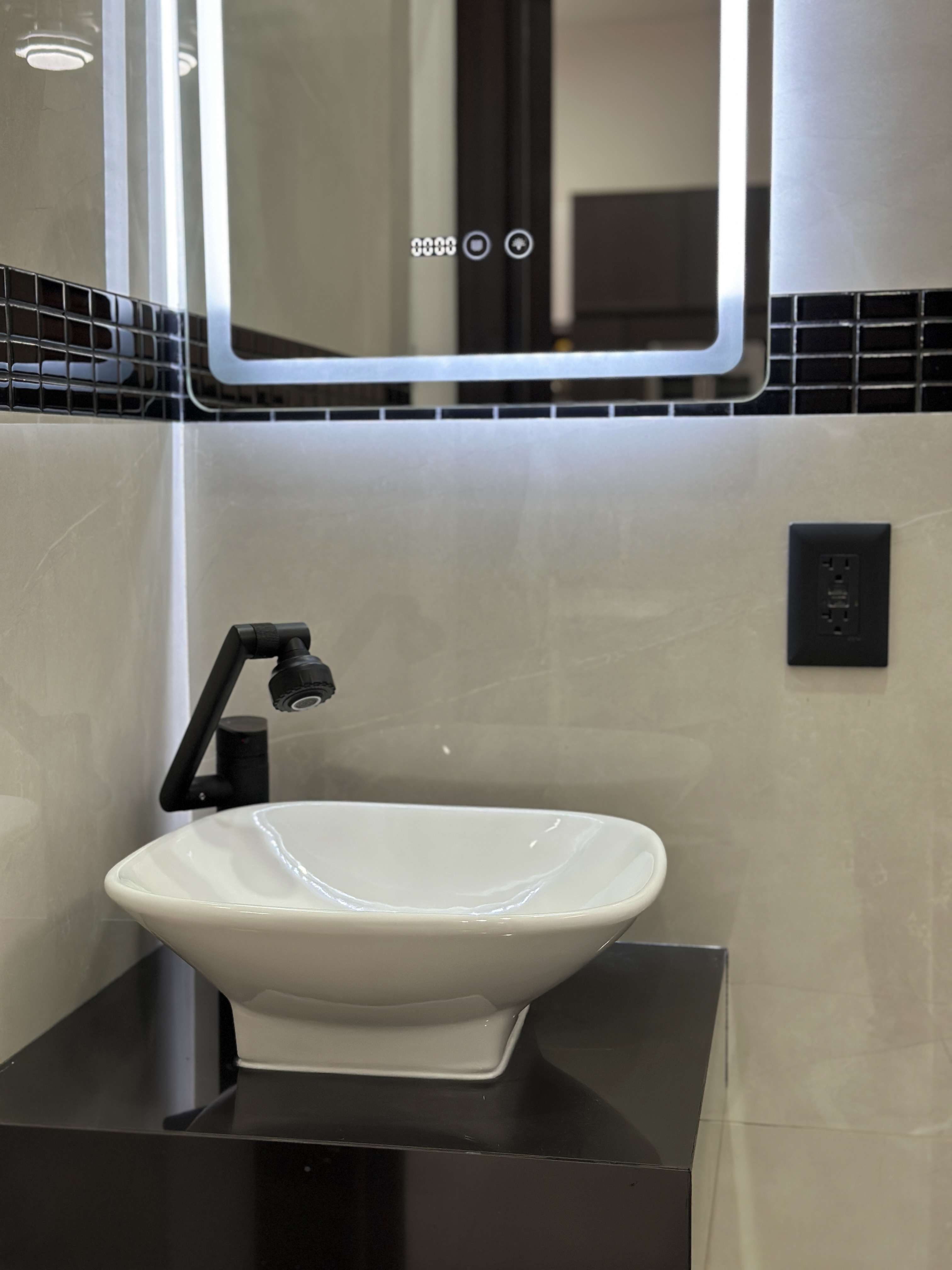 Detalle de lavabo de porcelana sobre tablero negro y espejo LED — Casa Manglar