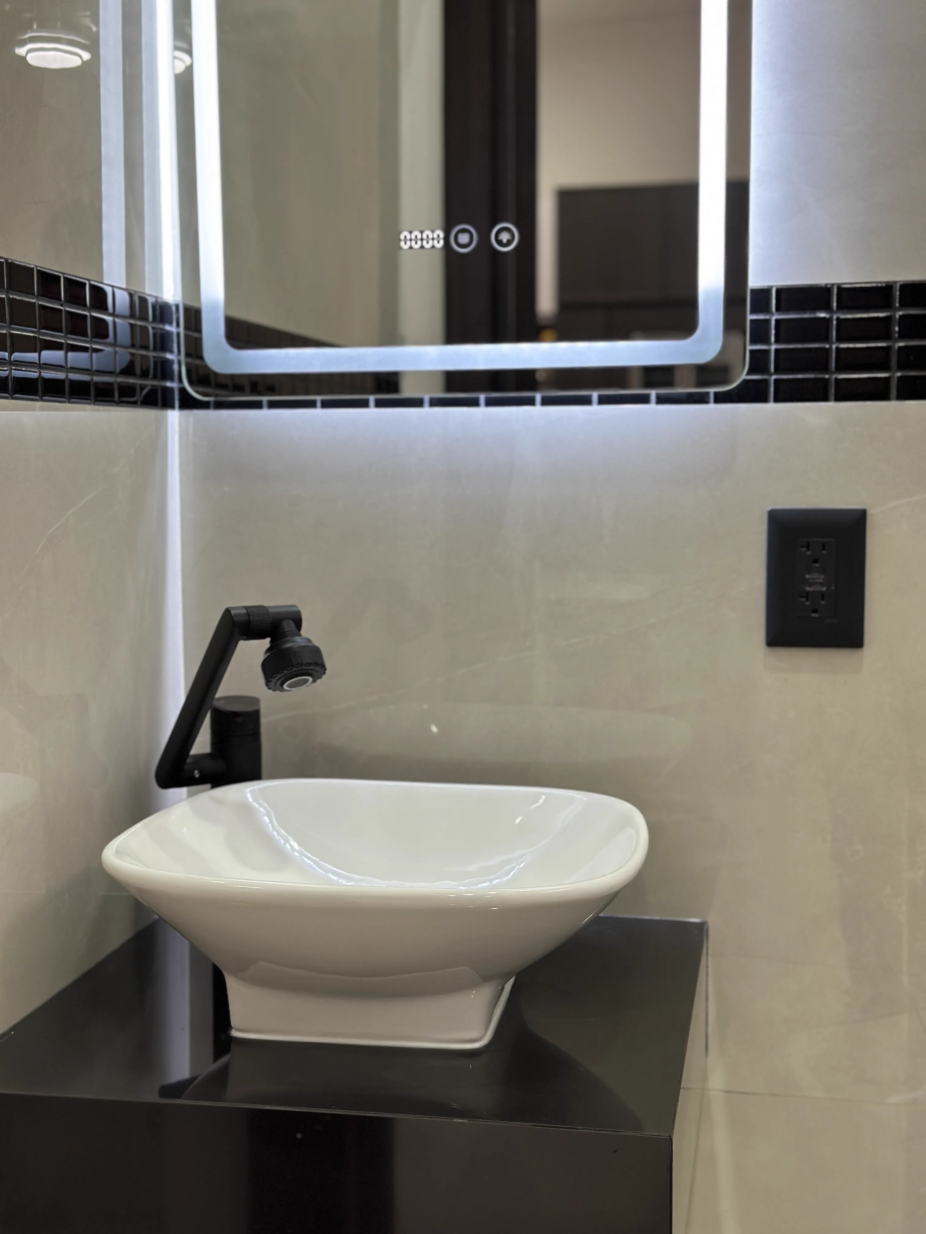 Detalle de lavabo de porcelana sobre tablero negro y espejo LED — Casa Manglar