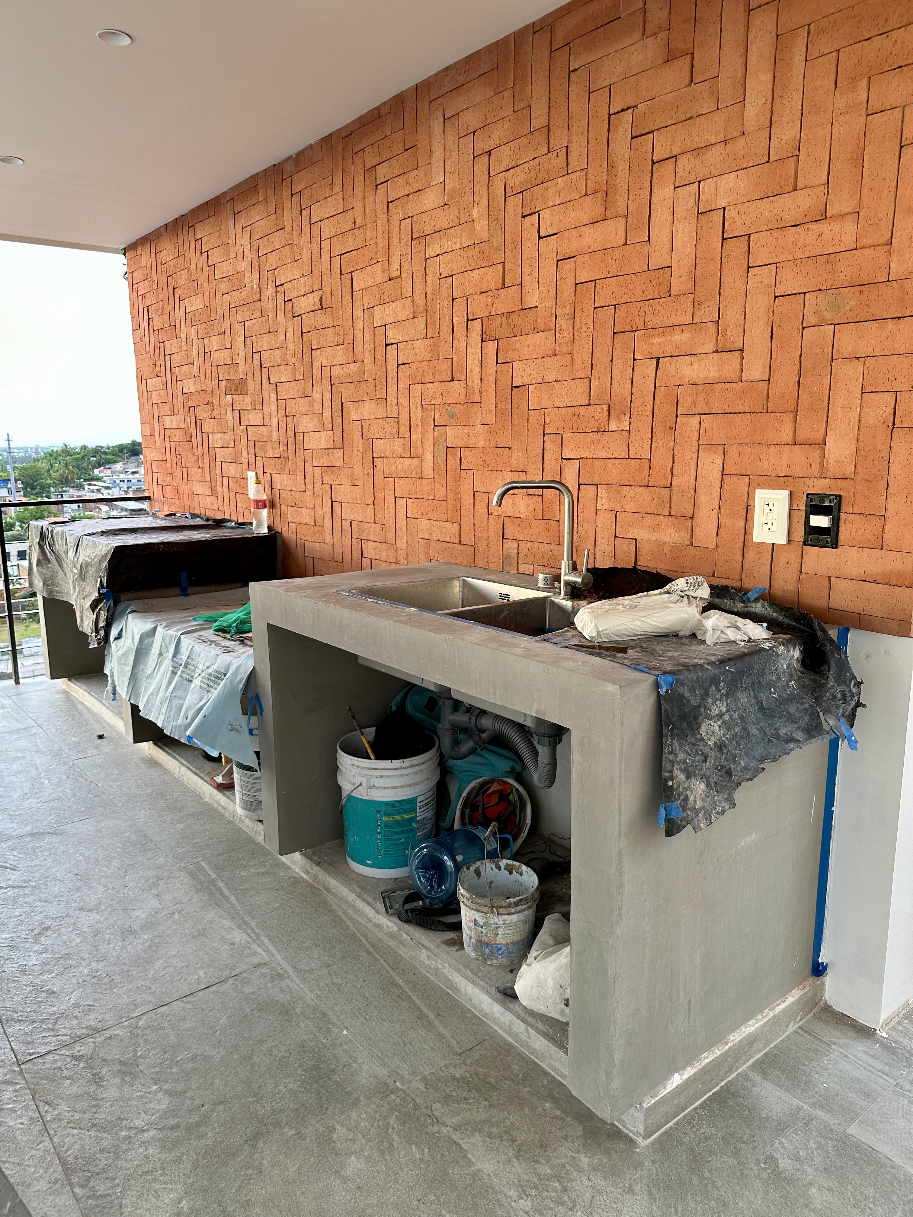 Terraza BBQ — concreto y ladrillo herringbone instalándose